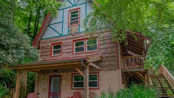 A log cabin with a porch, a staircase, and a sign indicating it is a chalet.