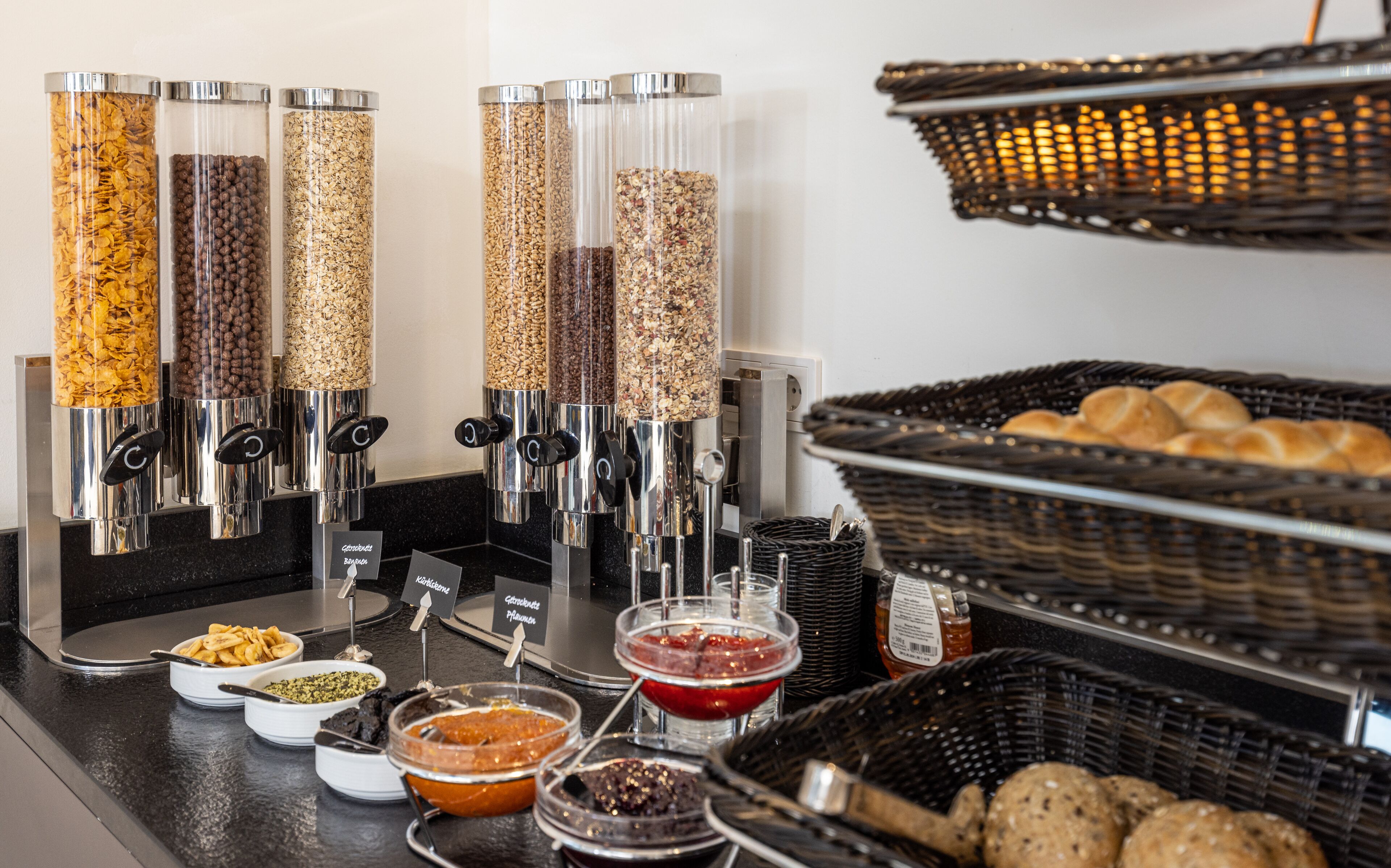 A breakfast buffet with various food options, including cereals, nuts, and spreads.