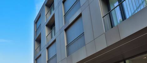 A modern building with multiple floors, large windows, and balconies.