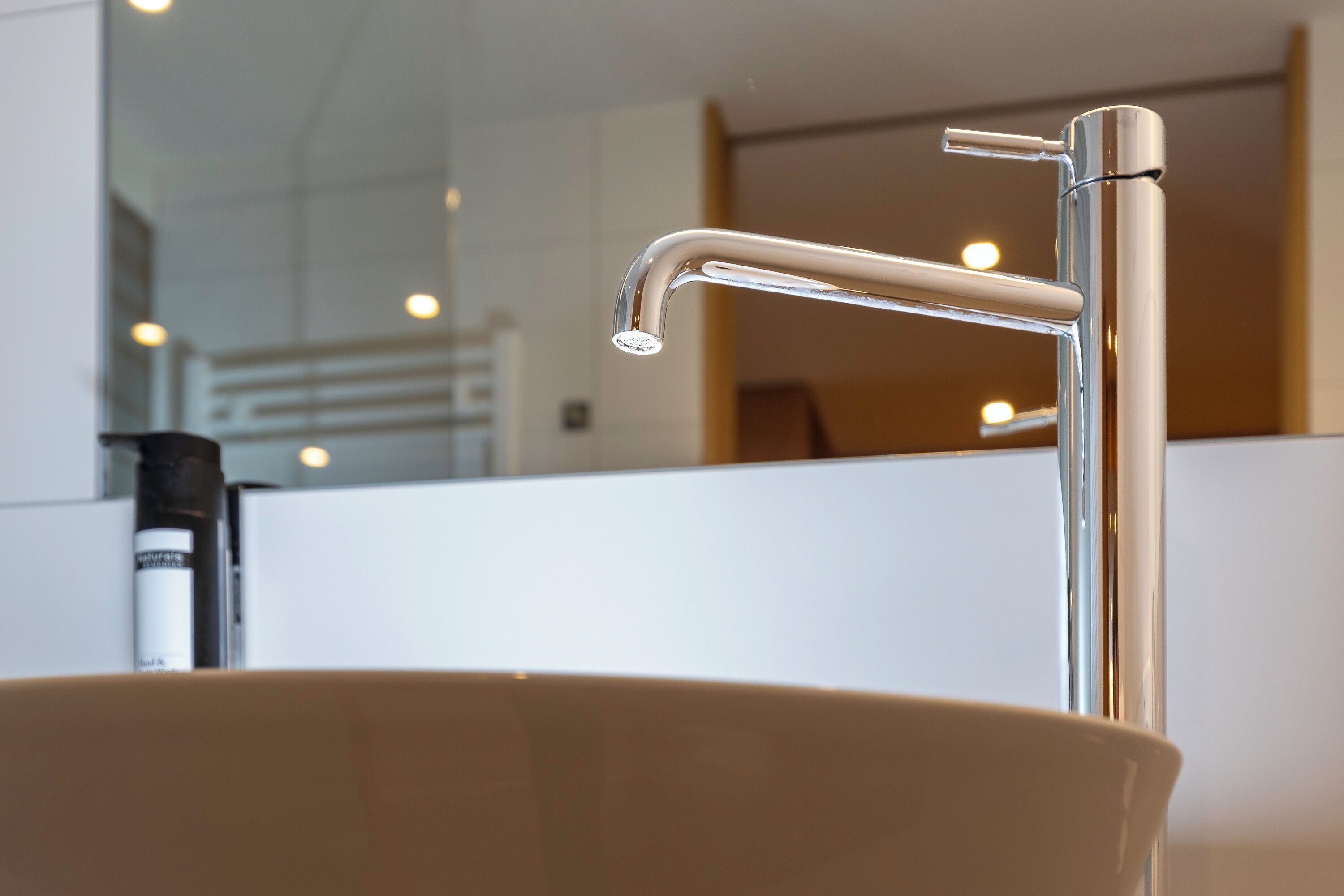 Un baño moderno con grifo cromado y lavamanos blanco.