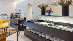 A buffet setup with various food stations, a coffee machine, and decorative vases.