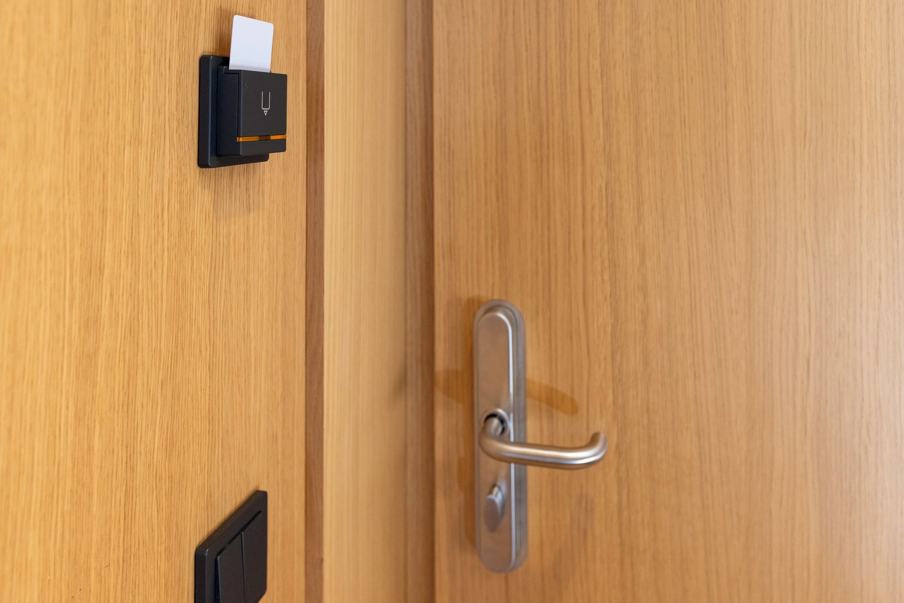 Una puerta de madera con manija de plata y un lector de tarjetas negro.