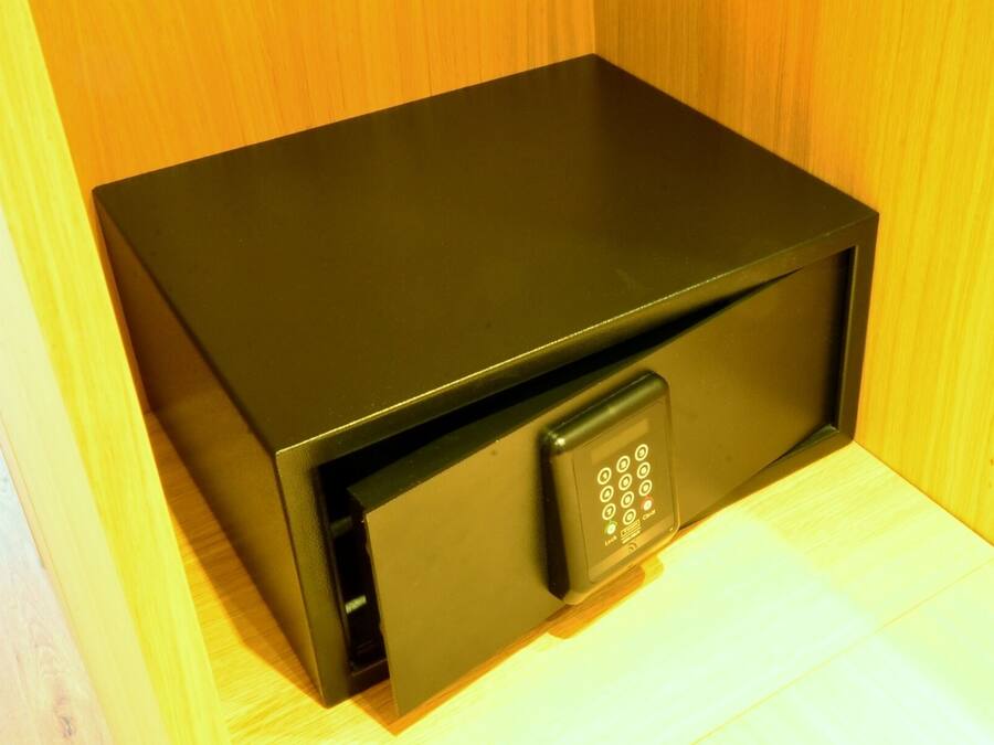 Un coffre-fort noir doté d’un clavier, placé devant un fond en bois.
