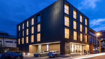 A modern hotel building with a prominent "HOTEL" sign, multiple windows, and a well-lit entrance.