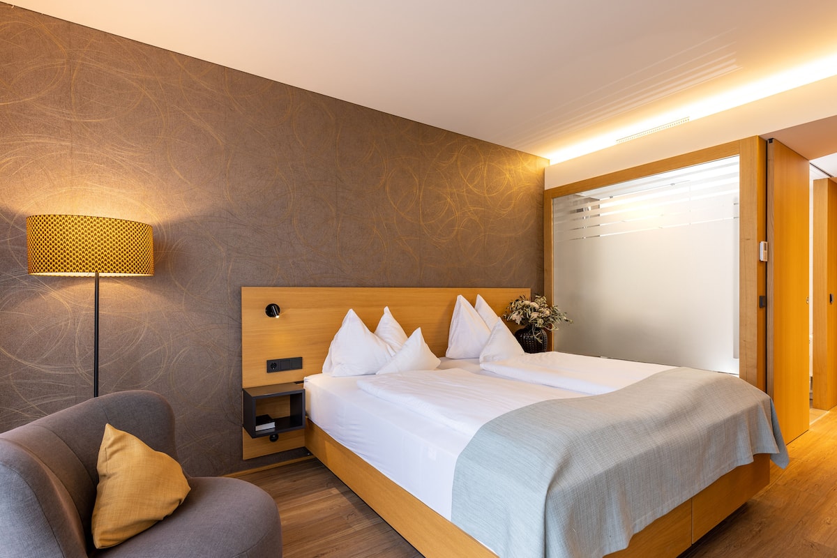 Ein modernes Hotelzimmer mit einem großen Bett, einem Nachttisch, einer Lampe und einem Kleiderschrank.
