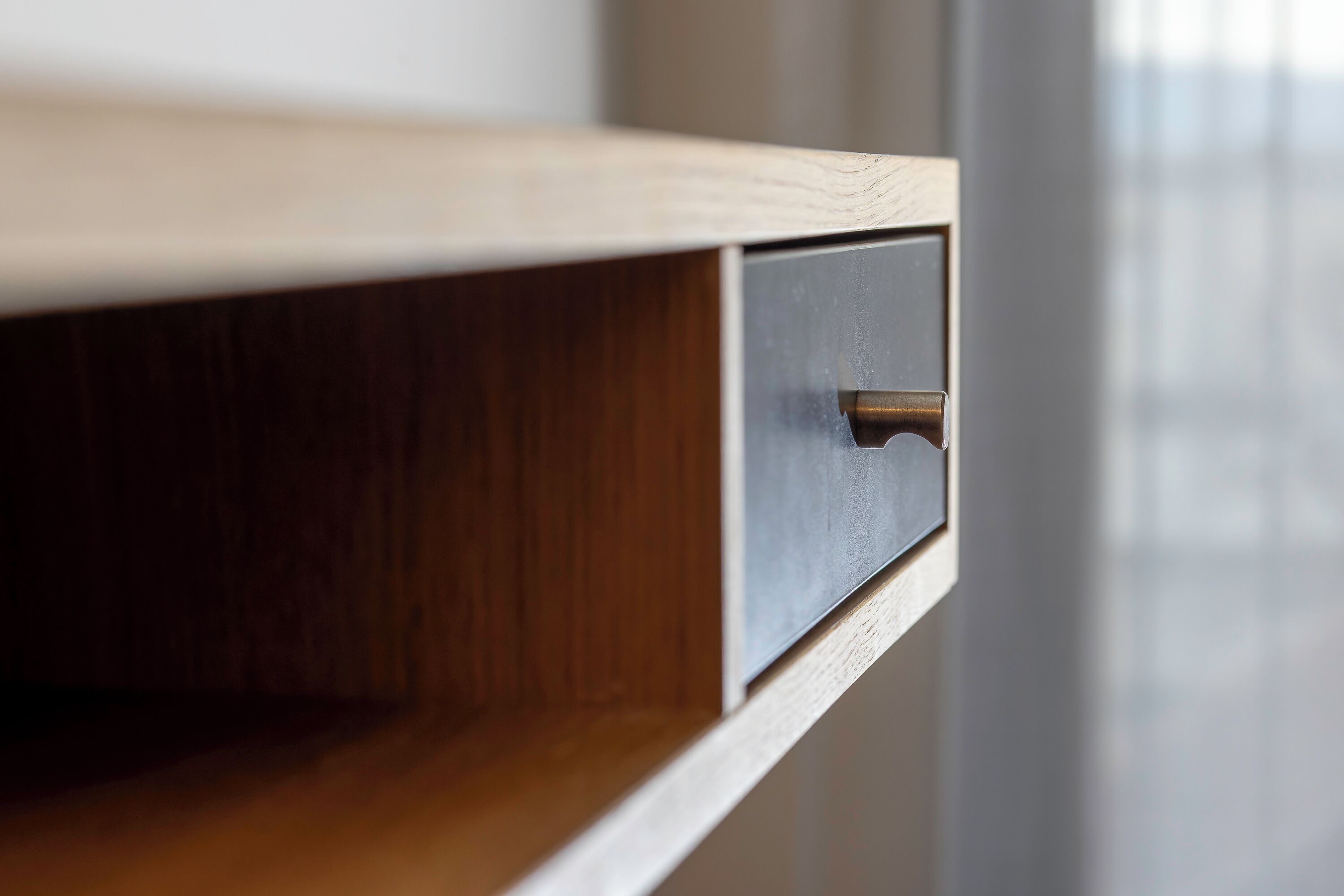Een houten kastje met een lade, een metalen handgreep en een metalen ladefront.