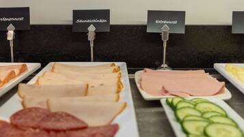 Un bufé con secciones identificadas para salchichas vienesas, jamón agridulce, salchichas especiales y queso Edamer.