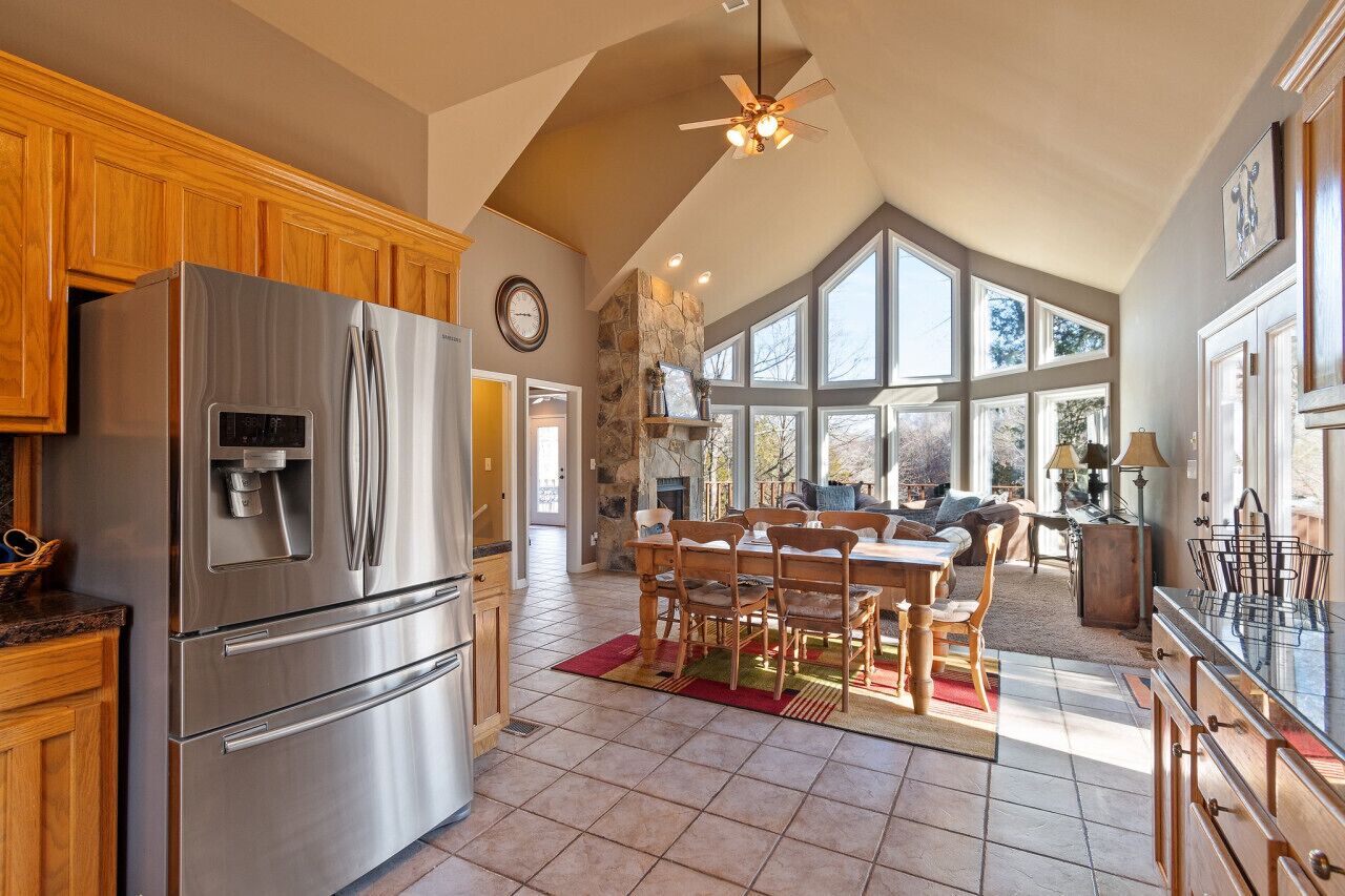 A spacious kitchen with a stainless steel refrigerator, wooden cabinets, and a dining area with a table and chairs.