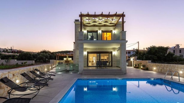 Un bâtiment à deux étages doté d’une piscine, de chaises longues et d’une pergola.