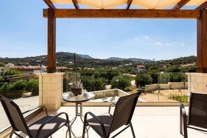 Enjoy the serene hilly landscape from this balcony with a comfortable seating area.