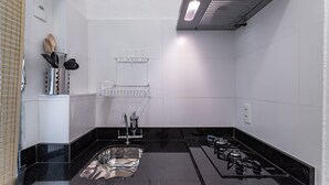Une cuisine moderne dotée d’un plan de travail noir, d’un évier en acier inoxydable et d’une cuisinière à gaz.