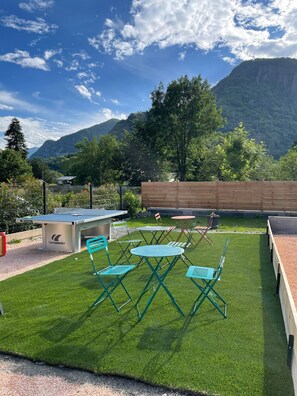 Relax in a serene outdoor space with a ping pong table, barbecue grill, and comfortable seating.