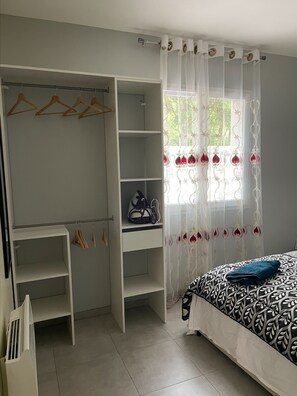 Cozy retreat with a large bed, wardrobe, and natural light pouring in through sheer curtains.