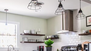 Une cuisine dotée d’un îlot central, de tabourets de bar, d’une cuisinière et de luminaires suspendus.