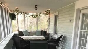 A porch with a table and chairs, a floral rug, and a view of the outdoors.
