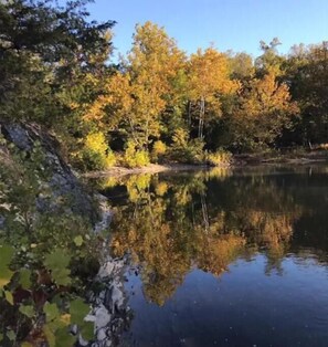 A calm lake surrounded by trees with autumn foliage.