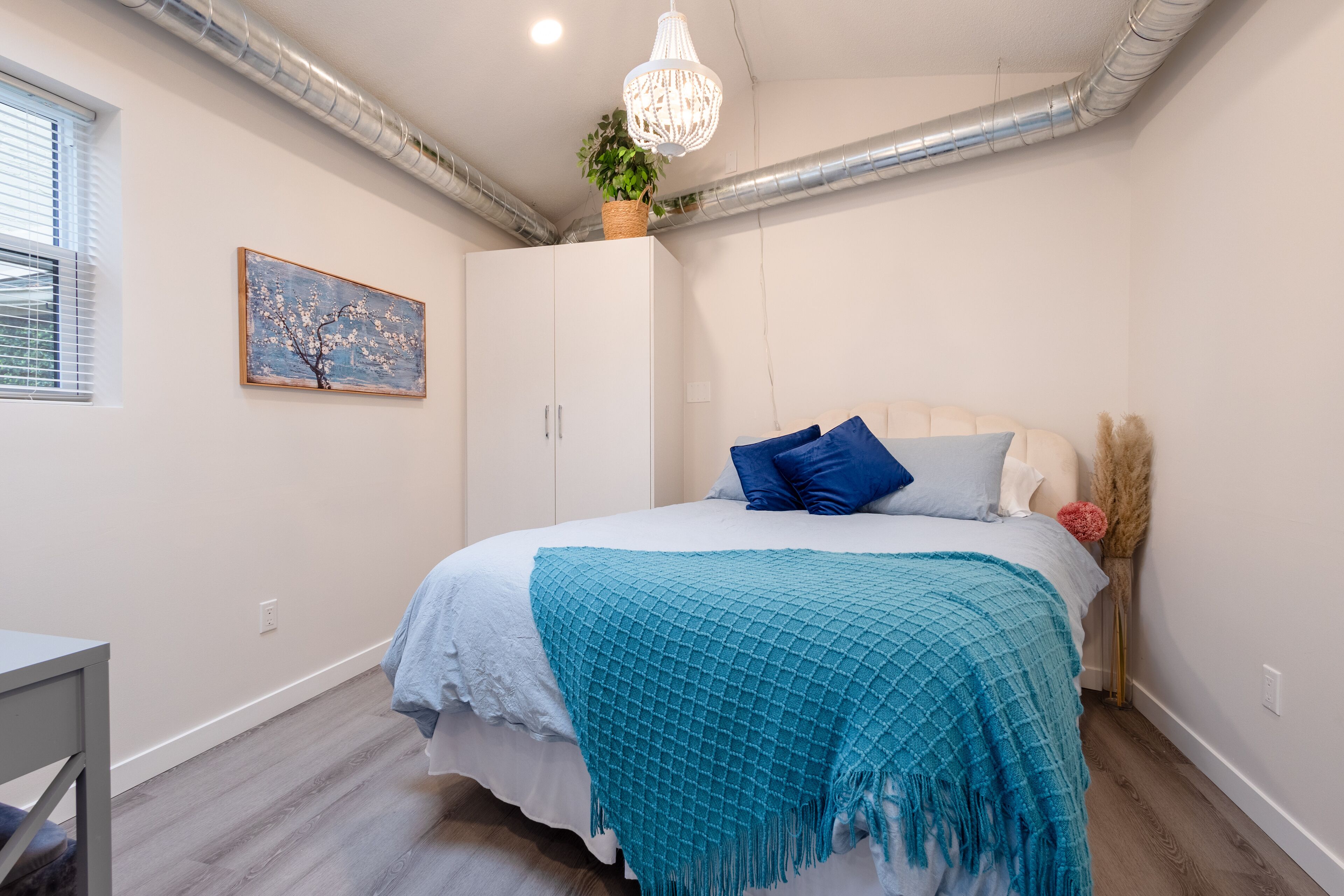 Une chambre à coucher avec un lit, un bureau, une fenêtre et un tableau.