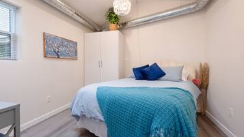 Une chambre à coucher avec un lit, un bureau, une fenêtre et un tableau.