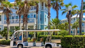 Een golftrolley geparkeerd voor een hotel met een zwembad en palmbomen.