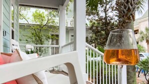 Een wit terras met een glazen tafel, een witte bank en een glas amberkleurig voer.
