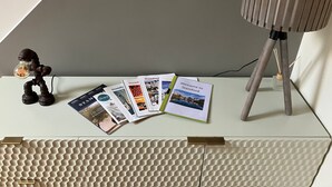 Una scrivania con una lampada, una piccola statuina e una pila di brochure di benvenuto.