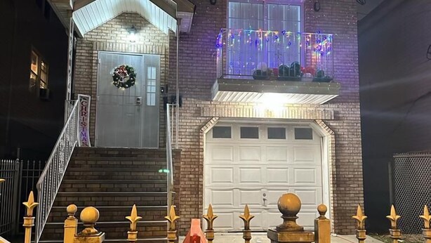 Une maison à deux étages avec une entrée à l’avant, un garage et un balcon décoré de guirlandes lumineuses.