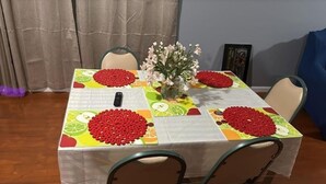 Une table à manger recouverte d’une nappe colorée, un vase rempli de fleurs et des fruits rouges en guise de décoration.