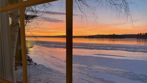 Udsigt over en frossen sø med solnedgang i baggrunden.