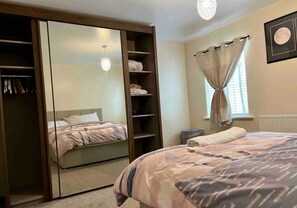 Cozy retreat with a large bed, wardrobe, and bedside table, perfect for a restful stay.