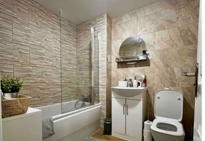 Bathroom features a glass-enclosed shower, bathtub, and raised toilet.