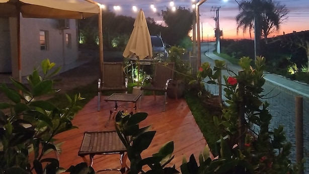 Un patio al aire libre con luces colgantes, una zona de estar cubierta y plantas en macetas.