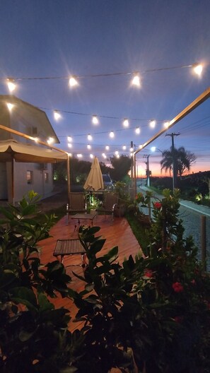 An outdoor patio area with string lights, a covered seating area, and potted plants. - Pousada Bella Vista - Vale dos Vinhedos (Bento Gonçalves)