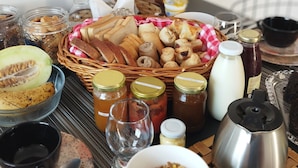 Una mesa de desayuno con diversos alimentos, como pan, bollería y salsas.