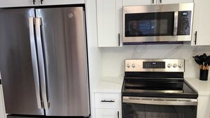 A modern kitchen with stainless steel appliances, including a double-door refrigerator, a microwave, and an oven.