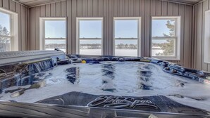 Uma banheira de hidromassagem com vista para uma paisagem nevada através de grandes janelas.