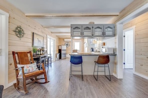 A kitchen with wooden walls, a bar area with stools, and a dining chair. - Waterfront with access, 3BR, Dock, Sauna & Hot Tub (Alberton)