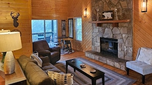 A cozy log cabin interior with a stone fireplace, wooden ceiling beams, and a comfortable seating area. - Southern Oak-Best views of the Mountains (Blairsville)