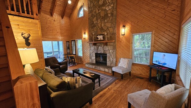 A cozy cabin interior with a stone fireplace, wooden walls, and a television. - Southern Oak-Best views of the Mountains (Blairsville)