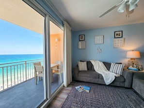 A room with a balcony, a sofa, a lamp, and framed pictures on the wall.