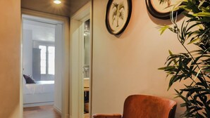 A hallway with a wooden chair, a plant, and framed pictures on the wall. - Apartments Florence- Pitti 8 with amazing view (Firenze)