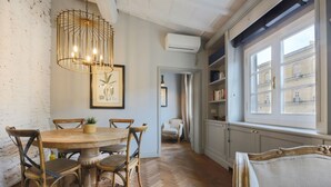 A dining area with a wooden table and chairs, a hanging light fixture, and a view of the outside through a window. - Apartments Florence- Pitti 8 with amazing view (Firenze)