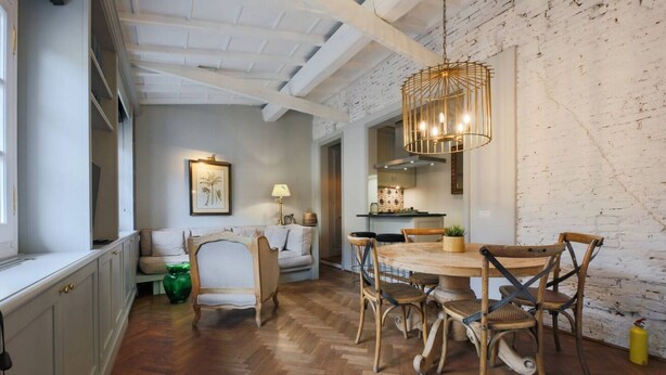 A dining area with a wooden table and chairs, a hanging light fixture, and a white brick wall. - Apartments Florence- Pitti 8 with amazing view (Firenze)