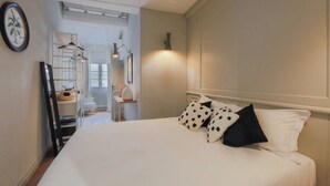 A bedroom with a bed, pillows, a bedside table, a lamp, a radiator, a wardrobe, and a mirror. - Apartments Florence- Pitti 8 with amazing view (Firenze)