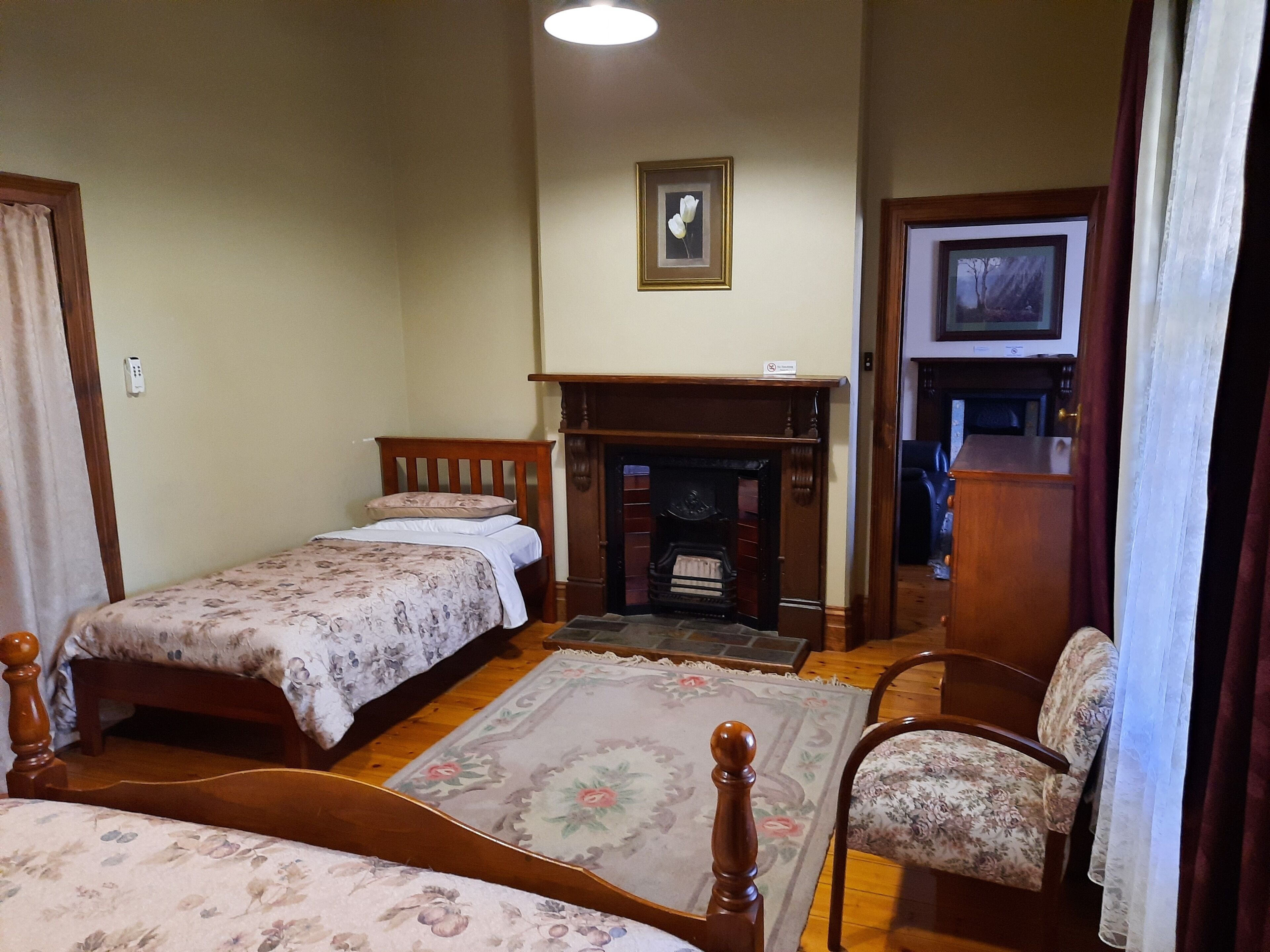 A bedroom with two single beds, a fireplace, a television, and a floral-patterned rug.