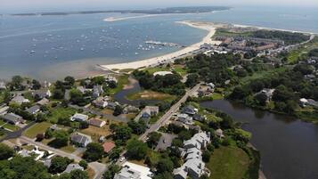 An aerial view of a coastal residential area with houses, a river, and a beach.