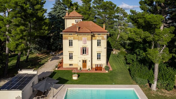 Un grand bâtiment à deux étages doté d’une piscine, entouré d’arbres.
