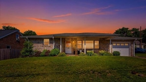 A single-story house with a stone facade, a front porch, and a garage.