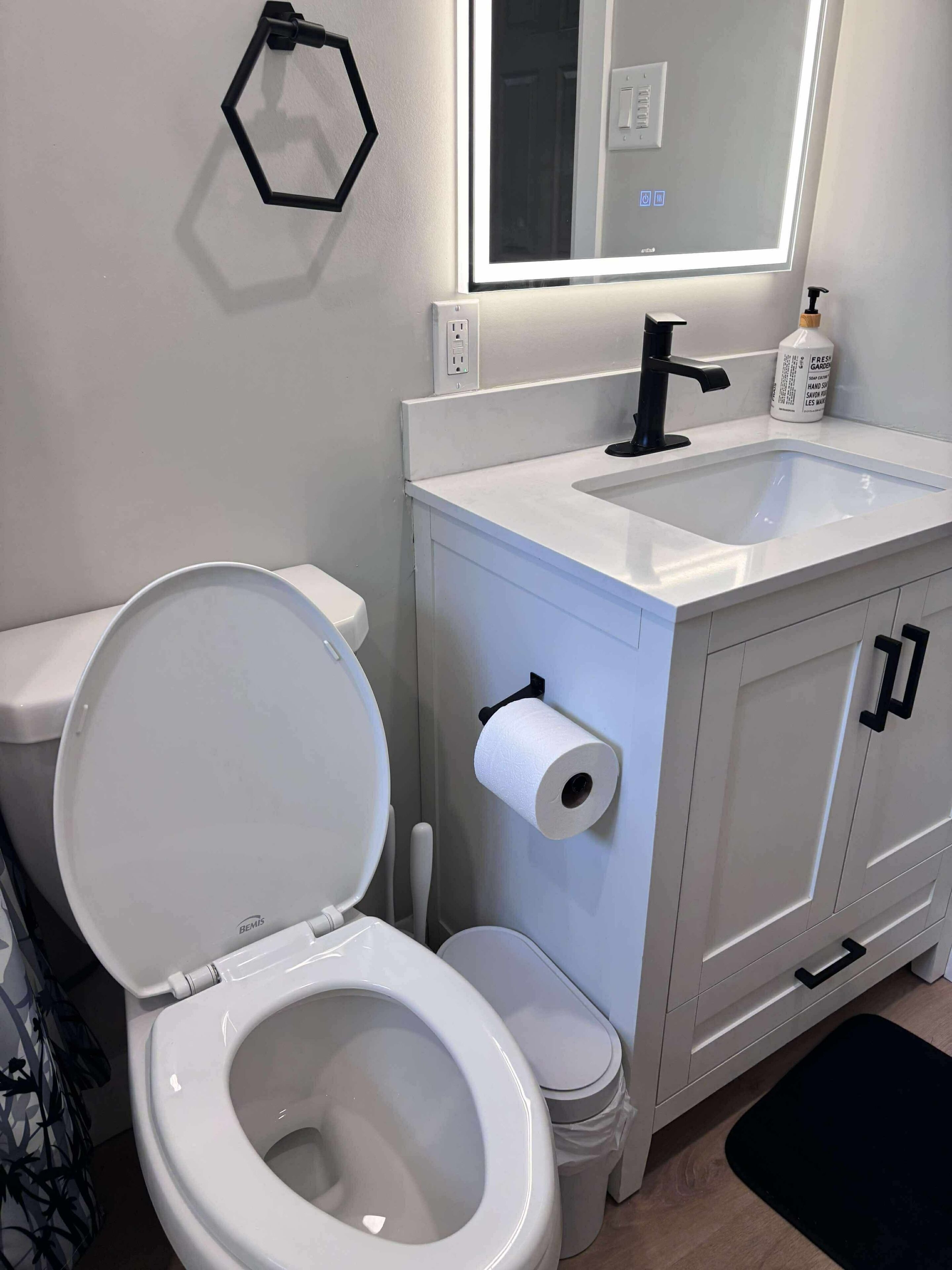 Een moderne badkamer met toilet, wastafel en spiegel.
