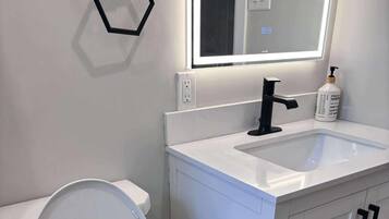 Een moderne badkamer met toilet, wastafel en spiegel.