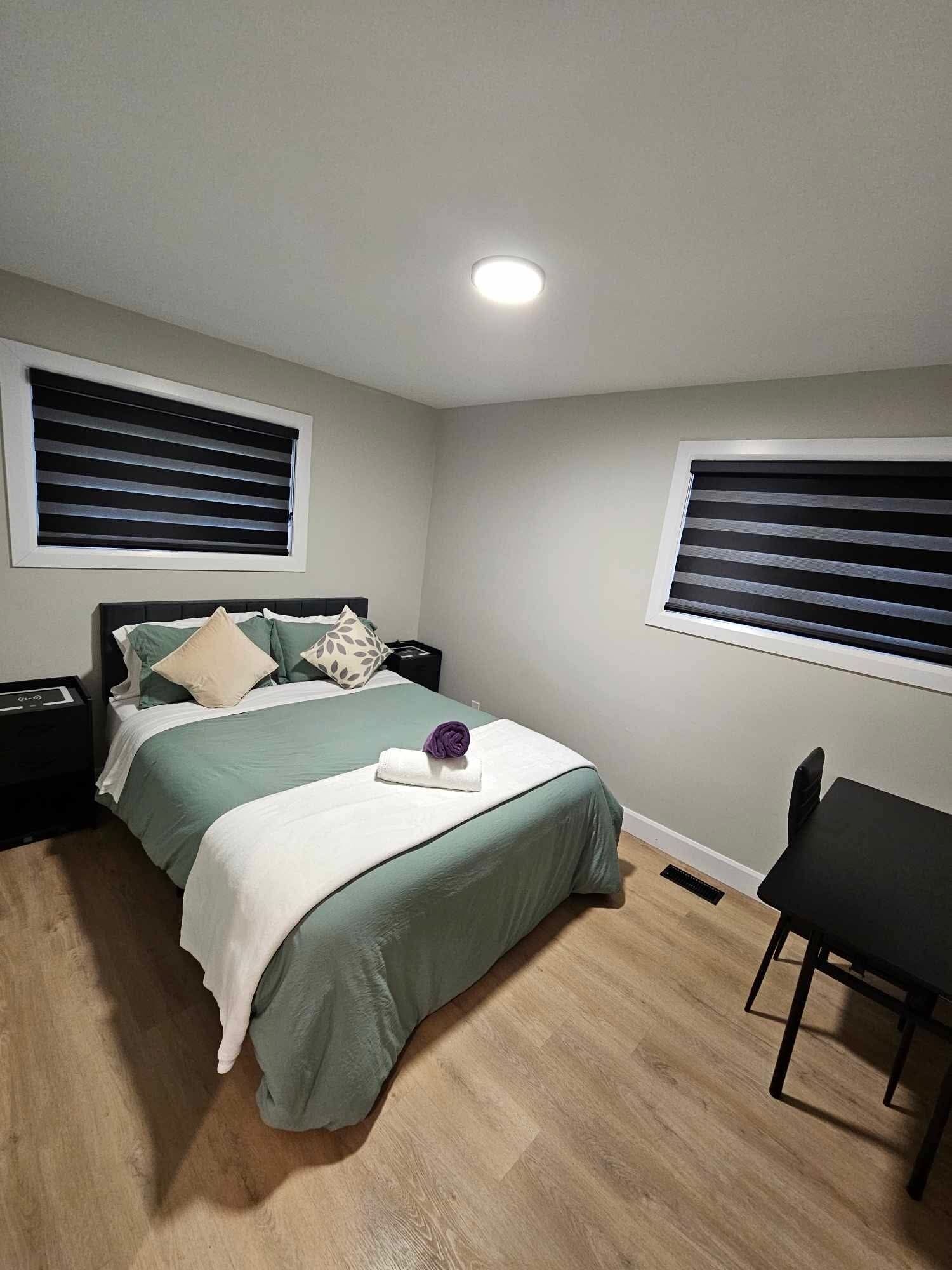 A bedroom with a bed, bedside tables, a chair, and a window with blinds.
